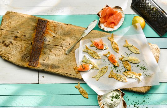 Aerial food photograph of fish shaped biscuits made with Welsh laverbread, topped with smoked salmon and cream cheese