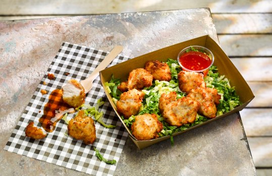 Food photograph close up of parmesan crusted chicken bites with chilli sauce and shredded lettuce