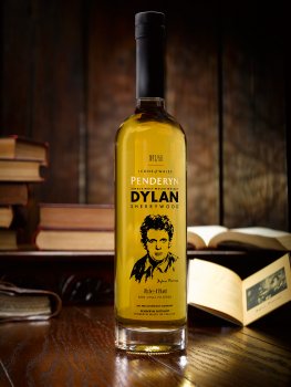 Photograph of a bottle of limited edition Penderyn Welsh Whisky commemorating Dylan Thomas. Shot in a dark wood setting with vintage Dylan Thomas poetry books.