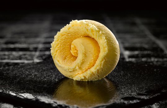 Photograph of a ball of vanilla ice cream shot on a black slate background to emphasise the colour contrast with the light coloured ice cream