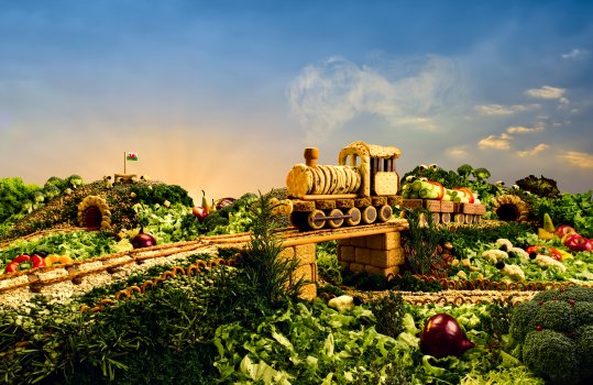 Photograph of a Welsh food landscape including a train on a railway bridge constructed from biscuits, going through a countryside landscape made from fresh vegetables